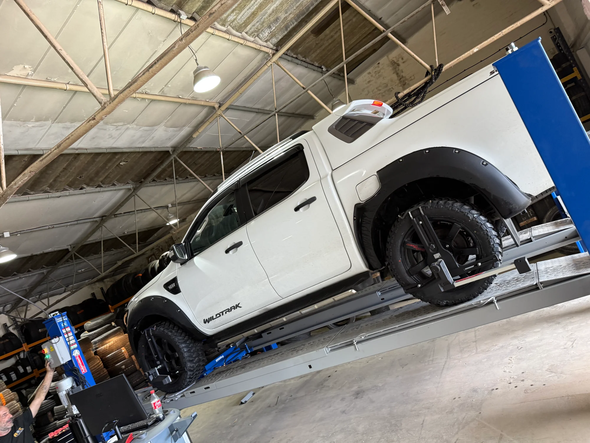 A ford pikcup on a ramp inside a garage.