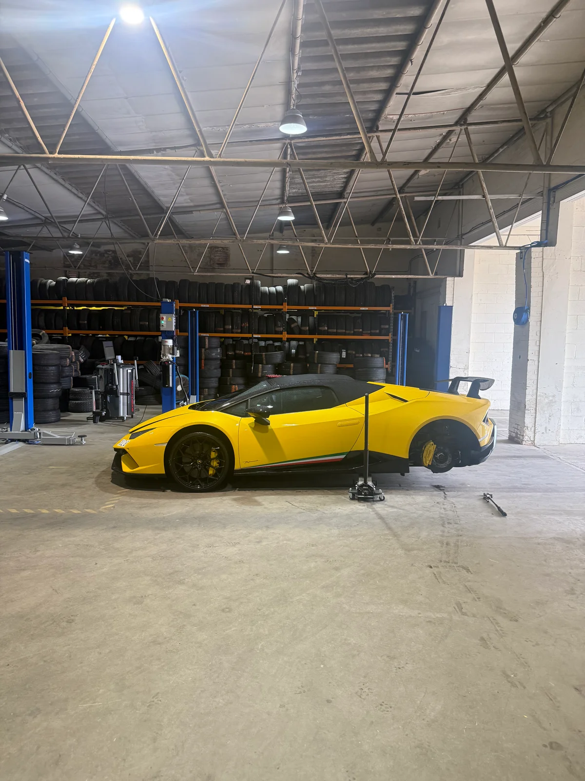 A yellow lamborghini on a ramp inside a garage.