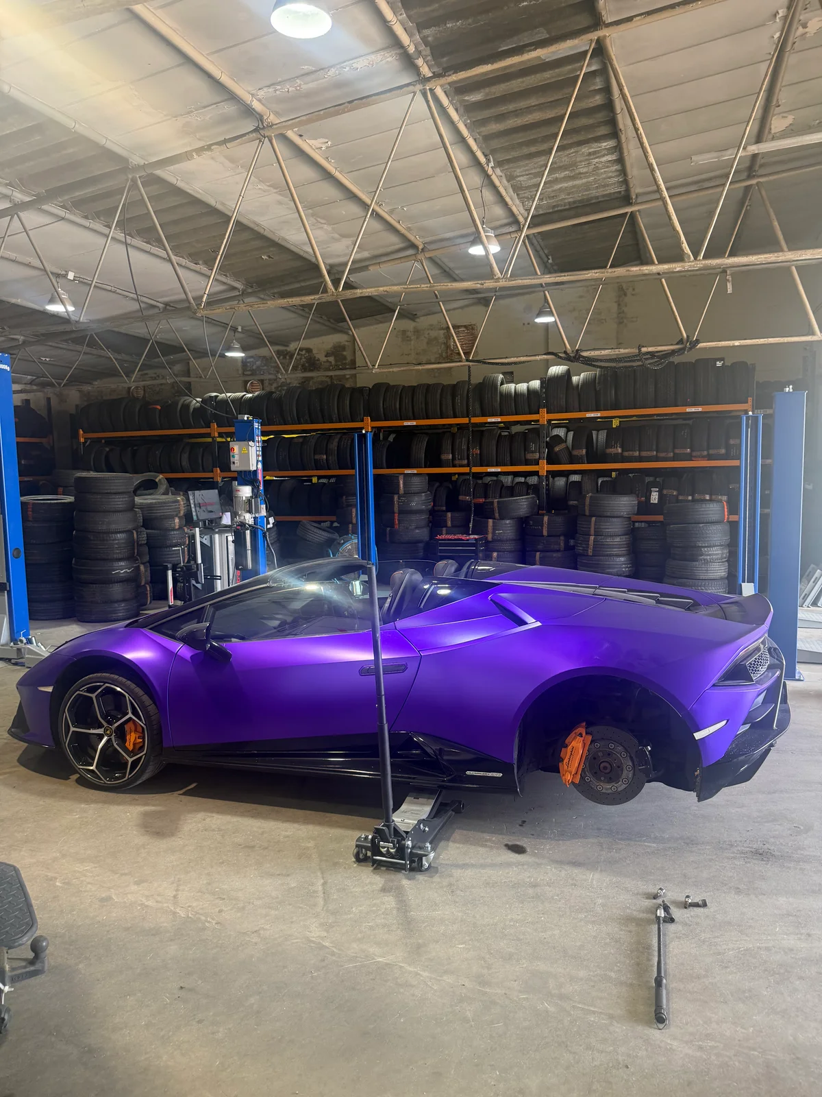 A blue lamborghini on a ramp inside a garage.