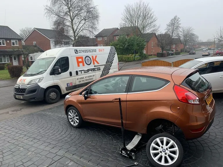 Orange Ford jacked up on a driveway