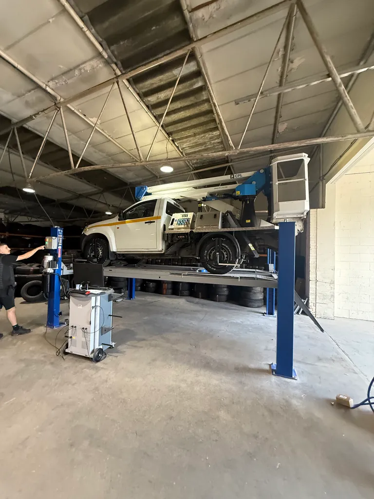 A Ford pickup on a ramp inside a garage.